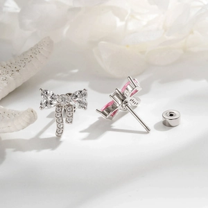 Elegant bow-shaped earrings with micro-inlaid zircons in silver and pink on a white surface