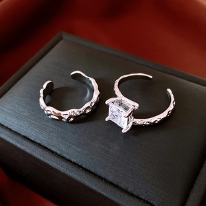 Detail of square zircon ring and silver lava texture open rings set on jewelry box