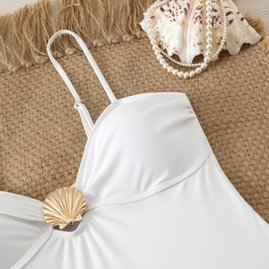 Close-up of white slim bodysuit with golden shell hardware on textured woven mat