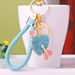 Blue heart rhinestone keychain with arrow and braided leather strap hanging on white cup