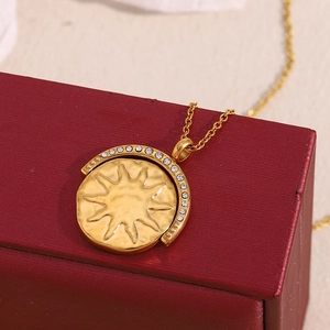 Detail shot of a sun relief pendant in 18K gold-plated steel with sparkling crystal halo