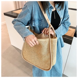 Detail of hand-woven straw tote with beige leather trim and matching inner pouch