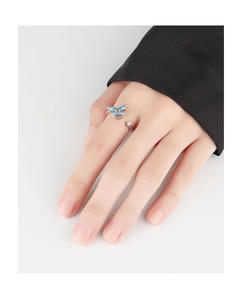 Detail of a rotating silver butterfly ring with blue gemstone inlay on a finger