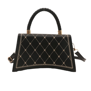 Chic black trapezoid handbag with beige quilted embroidery and golden metal accents