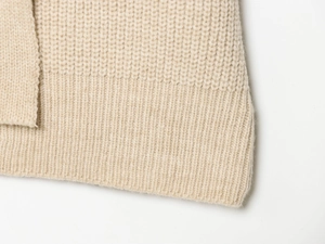 Gros plan sur le tricot beige avec ourlet côtelé montrant la texture de la maille