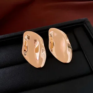 Irregular gold oval earrings with hammered texture displayed in a luxury jewelry box