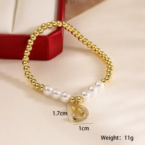 Macro shot of 18K gold beads and pearl bracelet with moon star pendant detail