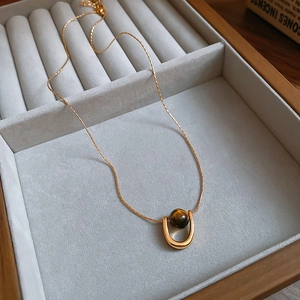 Detail of tiger eye stone bead in gold plated U-shaped pendant on jewelry display