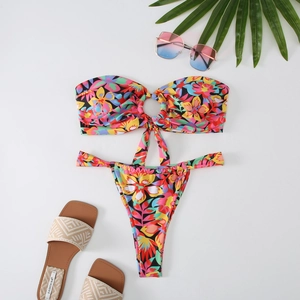 Detailed flat lay of tropical floral bandeau bikini with metal ring and summer accessories