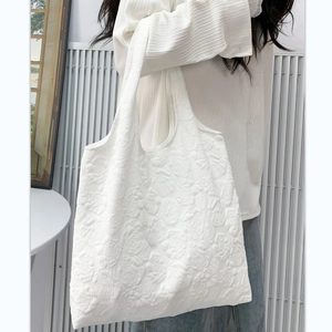 Detail of white tote bag featuring 3D rose textured fabric shown on model's shoulder