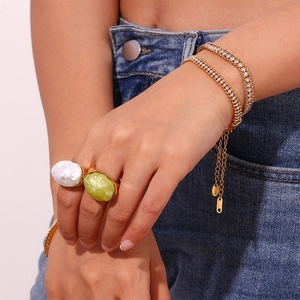 Detail of 18K gold-plated triple-layer zircon bracelet worn with large statement rings