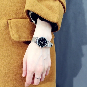 Detailed shot of a silver mesh strap watch with a black Roman numeral dial on a wrist