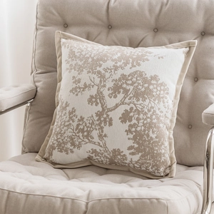 Close-up of beige jacquard pillow cover with tree texture on an upholstered chair