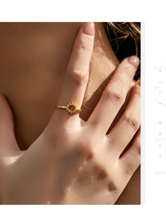 Detail shot of a minimalist gold sunburst ring on finger with radiant rays design