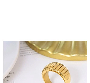 Macro shot of a wide gold-plated ribbed ring highlighting the intricate striped texture