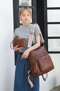 Detailed view of dark brown vintage leather backpack with tassel and matching small pouch