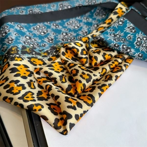 Detailed macro view of leopard print and floral pattern silk scarf with black stitched edges