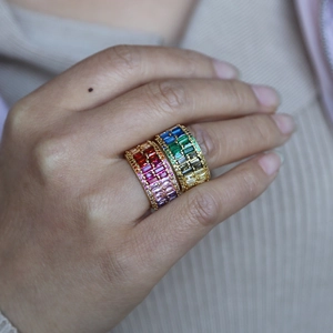 Close-up of gold rings with colorful rectangular zircon stones worn on fingers