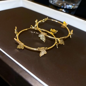 Macro shot of gold-plated hoop earrings with textured 3D butterfly charms