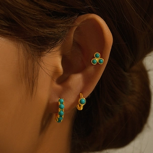 Close-up of a woman wearing gold-plated turquoise stud earrings and hoop set in French style