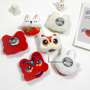 Detailed view of plush rabbit and lion dance pins with metal broach base and fine embroidery