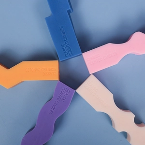 Close-up of colorful wave-shaped geometric candles with embossed classic scent text