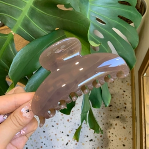 Minimalist translucent purple resin hair claw clip shown in a natural outdoor hand-held shot
