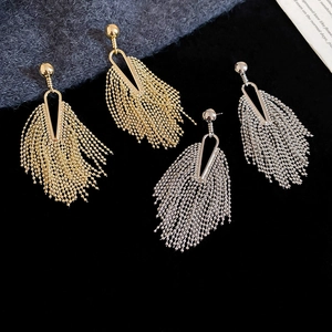 Detail view of gold and silver tassel drop earrings on black velvet with premium metal finish