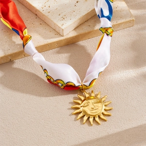 Collier en ruban imprimé floral avec un grand pendentif soleil doré sur pierre beige
