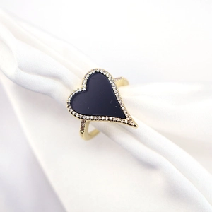 Detail of gold heart ring with black stone and pavé zircon on silk fabric background