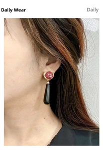 Close-up of vintage drop earrings with red marble stone and black teardrop pendant