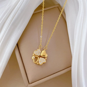Macro view of gold-plated clover necklace with two polished and two crystal-set hearts
