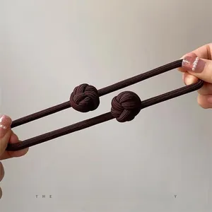 Detailed close-up of dark brown elastic hair tie showing stretch durability and dual knots