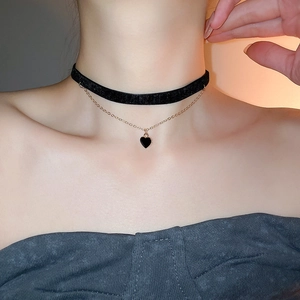 Close-up of double-layer black velvet choker with a gold heart pendant on neck