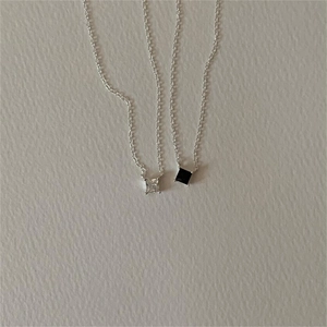 Detail of square-cut clear and black zircon pendants on minimalist silver chains