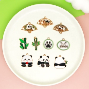 Flat lay of panda enamel charms for DIY jewelry on a white ceramic plate