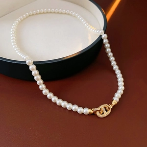 Detail of white pearl necklace with golden pavé-set zirconia chain link buckle