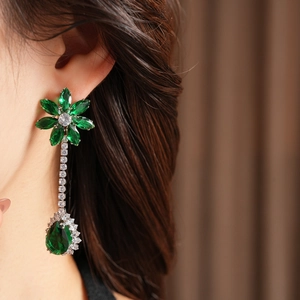 Detail of luxury green zircon flower earrings with long tassels on a female model