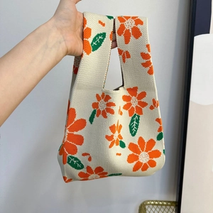 Detailed close-up of knitted tote bag showing cream base with orange flower patterns
