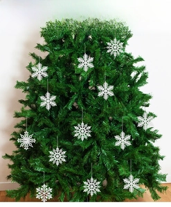 Close-up of 12 white 10cm hollow plastic snowflakes hanging on a green Christmas tree branch