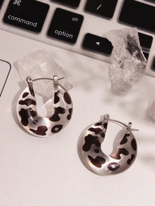 Detail view of chunky leopard print resin hoop earrings on a metallic surface