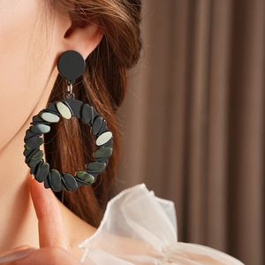 Close-up of geometric circular earrings with green stone patterns on a female model