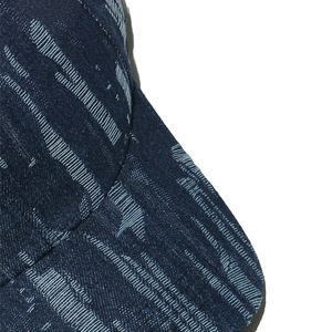 Macro view of blue denim baseball cap showing distressed texture and white stitching details