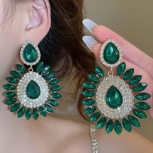 Close-up of luxury emerald crystal drop earrings with sparkling rhinestones on golden base