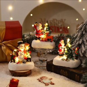 Detailed view of glowing resin Christmas ornaments with warm LED lights and faux snow base
