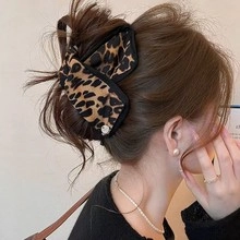 Detail of leopard print bow hair clip with black piping and pearl on model
