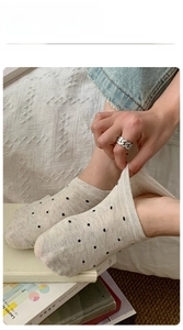 Detail of grey polka dot no-show sock showing high elasticity on white bedding background