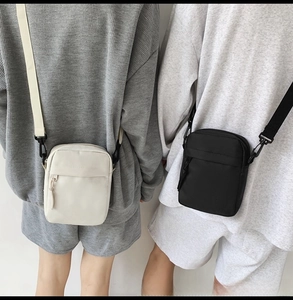 Detail shot of black and beige nylon crossbody bags with adjustable straps on a model