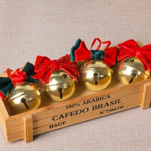 Christmas red velvet bows with golden metal bells displayed in a vintage wooden tray
