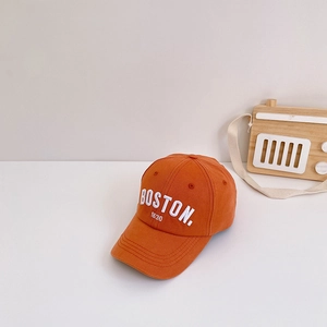 Detail of orange cotton baseball cap with white Boston embroidery and decorative toy